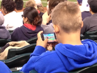 Illustration for article titled Bored Baseball Fans Play Baseball Video Games At Baseball Game